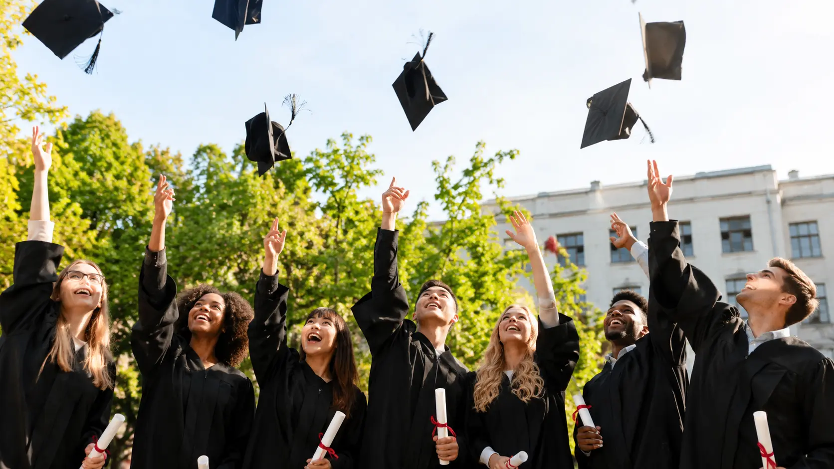 College graduates celebrating commencement by tossing their caps